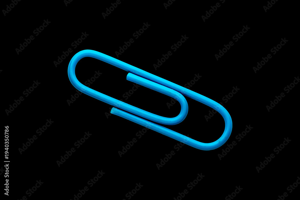 Obraz premium Blue metal paper clip cut out and isolated on a black background, minimal studio stock photo of a single office stationery item