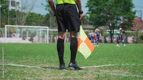 Soccer linesman watching the game on a green field, sports officiating concept