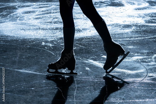 Quadro su tela Close up of figure skater legs and blades on a shiny indoor ice rink with reflection and shadow