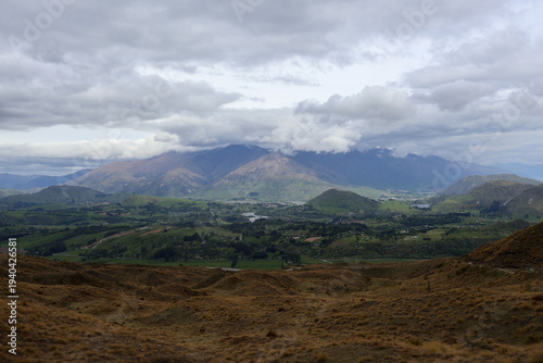 Cuadro en lienzo A wide vista showcases a lush valley nestled between rolling hills and imposing mountains