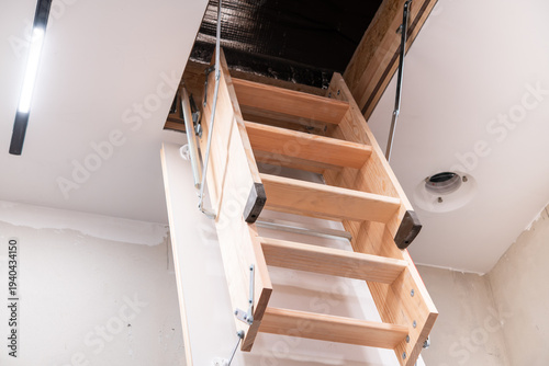 Wooden foldable attic ladder installed in ceiling opening