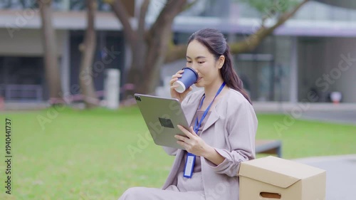  A cheerful businesswoman stands in her office, using a digital tablet to work on a financial project.