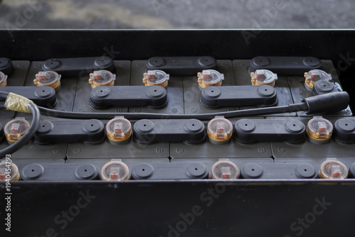 A stack of black locomotive batteries with yellow caps. Lead Acid Battery Box for Forklift at Cargo Pallet.