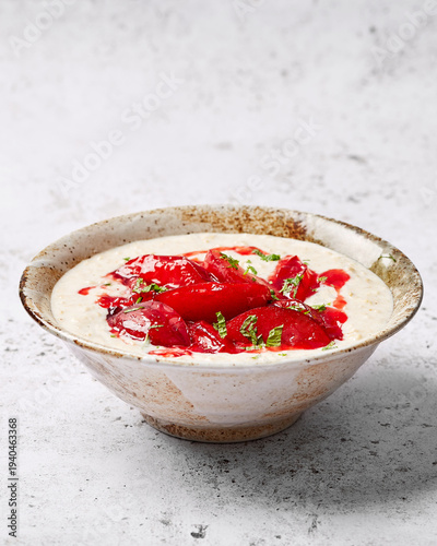Vanilla Porridge with Caramelised Plums and Mint in Bowl on Neutral Background