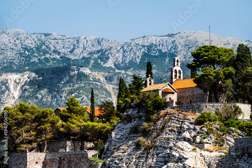 Scenic town on rocks in Montenegro with mountains on background Beautiful Mediterranean architecture with nature in sunny day