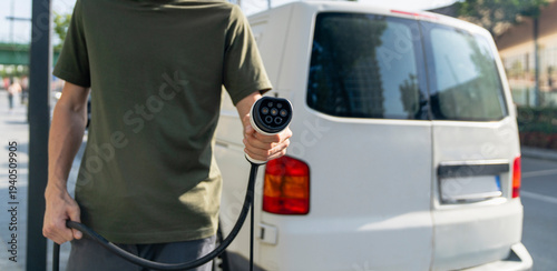 Wallpaper Mural Driver with charging plug next to of electric van Torontodigital.ca