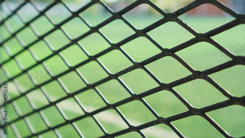 Close up of metal wire fence with blurred green field background