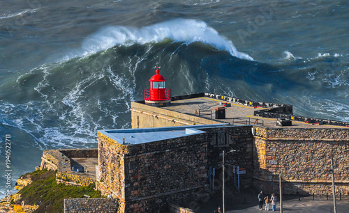 Giant Atlantic wave rising behind Nazare lighthouse Portugal