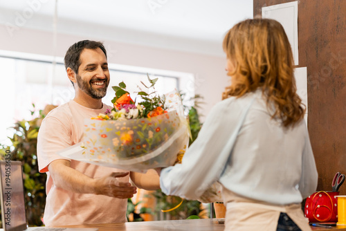 Florist giving bouquet of flowers to customer in flower shop