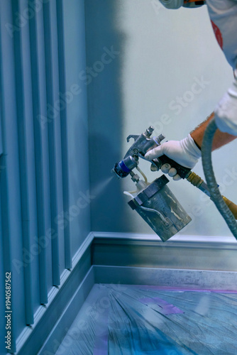 Construction worker spray painting interior wall using airless paint sprayer