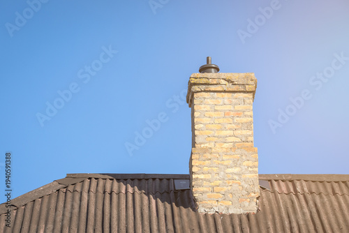 Brick Chimney on Corrugated Roof Against Clear Blue Sky