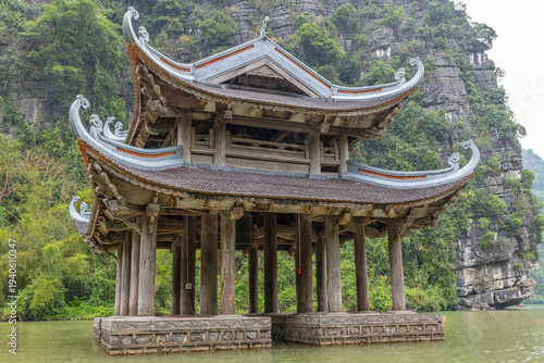 Traditional vietnamese wooden temple pavilion on water with limestone mountains in hoa l