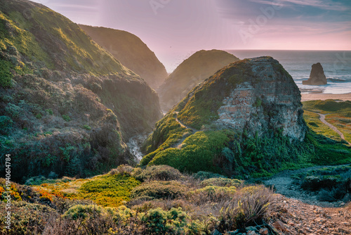 Scenic coastal landscape near Davenport Beach, California, featuring green hills, rugged cliffs, and a narrow valley leading toward the Pacific Ocean under soft natural light