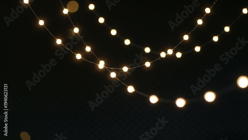 String of warm white fairy lights glowing softly in dark night background