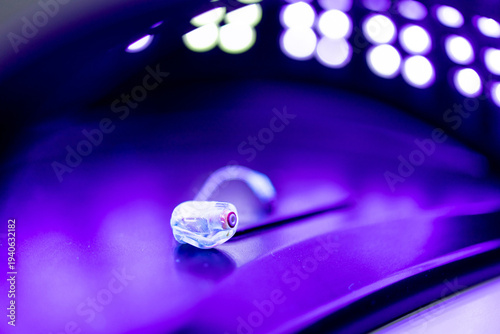 Tableau sur toile Photograph of a hearing aid in an ultraviolet light device for disinfection