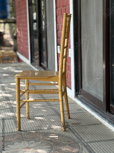 A yellow chair is sitting on a tiled floor outside