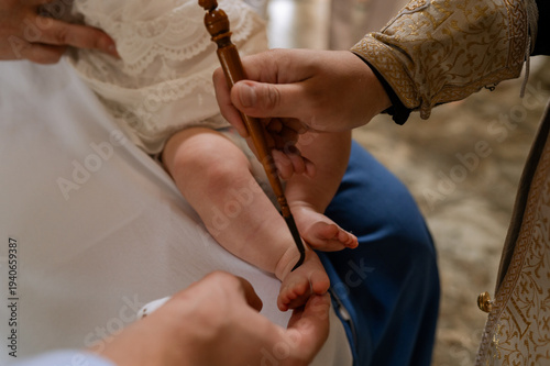 Fotografia Orthodox priest anointing newborn baby foot with holy oil during baptism ceremon