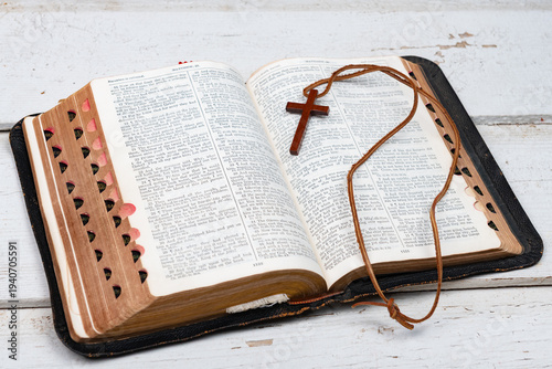 A wooden cross necklace on an open Bible with a shallow depth of field
