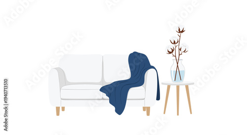 A simple white sofa with a blue blanket and a side table holding cotton branches is presented on a clean white background.