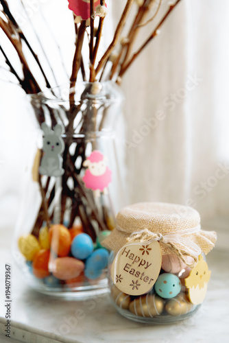 Easter jar with Easter eggs and DIY bouquet in a vase on the windowsill in the salon.