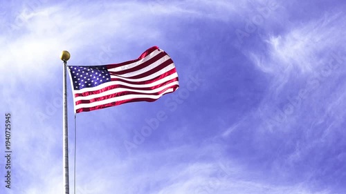 United states of america flag waving in the wind on a flagpole in slow motion video. The national emblem with stars and stripes against a bright blue sky