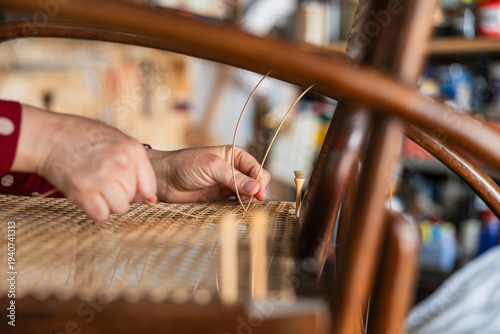 Tableau sur toile Artisan's hands meticulously weaving rattan fiber, restoring a vintage thonet st