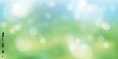 Abstract spring nature background featuring soft defocused bokeh lights over fresh green grass and clear blue sky. Perfect for spring season concepts, Easter designs, and eco-friendly themes.