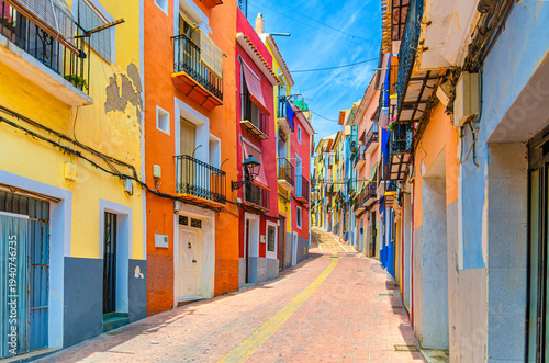 Villajoyosa old town narrow empty pedestrian street with typical colorful houses traditional multicolored buildings in sunny summer day, La Vila Joiosa city historic centre, Alicante province, Spain