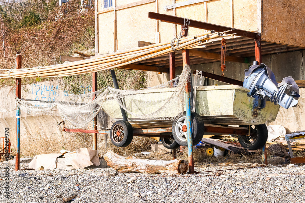 Fototapeta premium Stored boat under metal and wood canopy on gravel beach (55 chars)