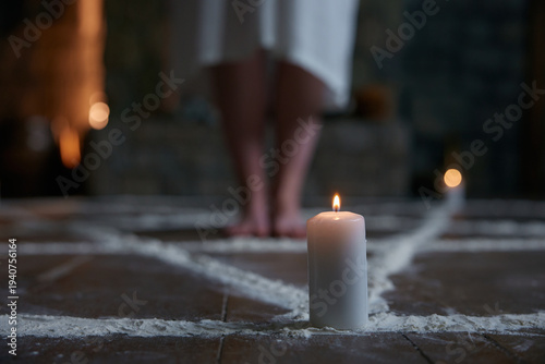 Candlelit chalk circle with barefoot practitioner standing near stone hearth