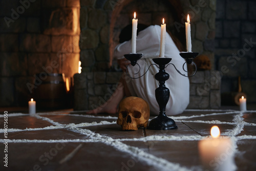 Canvas Print Woman kneeling behind candleholder near skull