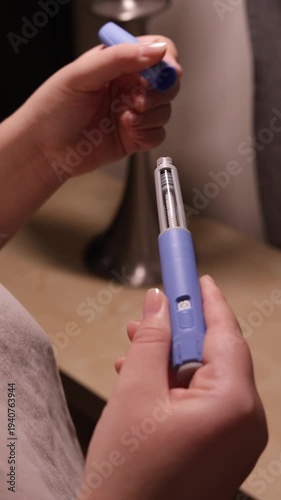 A vertical close up of a young woman screws a needle on pre-filled pen injector with semaglutide to prepare it for taking medicine
