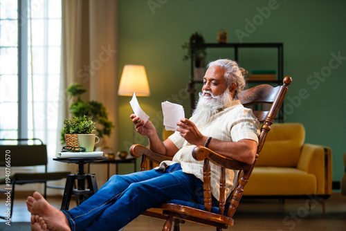 Canvas Print Bearded Indian man remembering family moments looking at photographs with teary