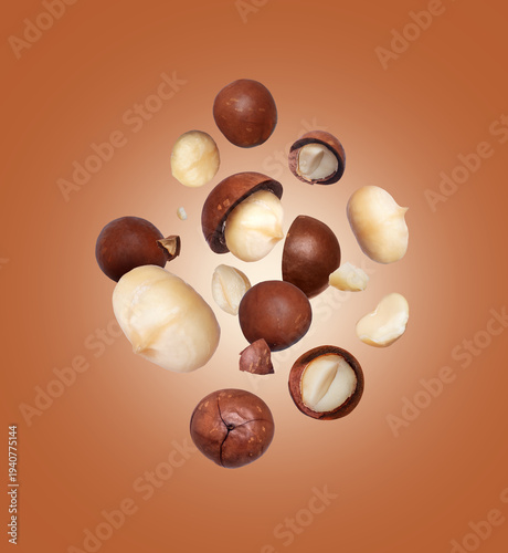Cracked macadamia nuts in the air close-up on brown background