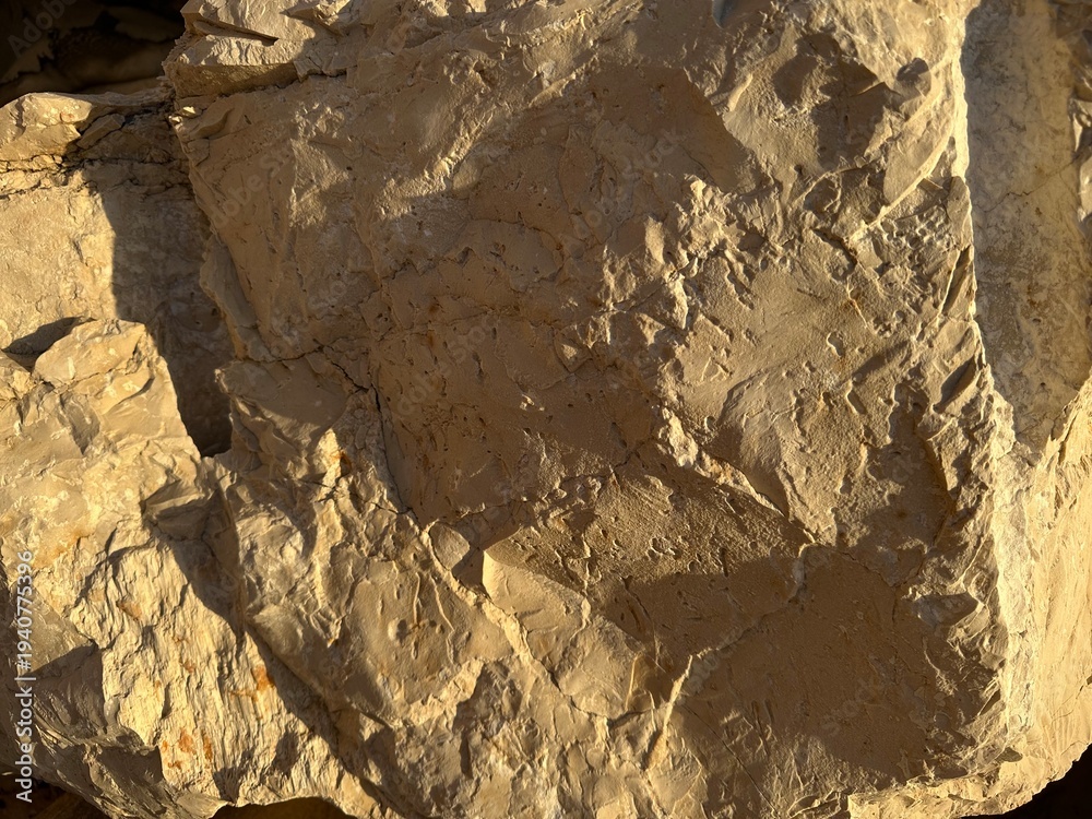 Fototapeta premium Rough fractured limestone rock surface in warm light