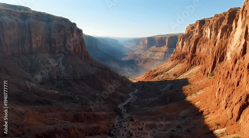 Vast canyon carved by river, sandstone cliffs glow under morning sun, distant mountains fade