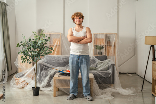 Bild auf Leinwand Young man standing in living room during home renovation project