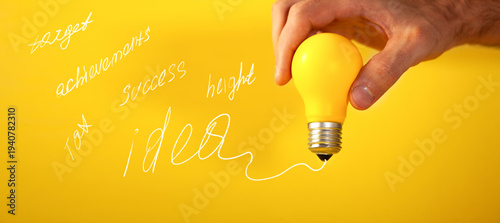 Hand holding a yellow lightbulb on a yellow background with the text