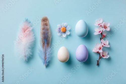 Pastel Easter eggs, feathers, daisy and cherry blossoms arranged in a row on light blue background.