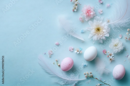 Pastel Easter eggs, white feathers and delicate spring flowers arranged on a light blue background with copy space.