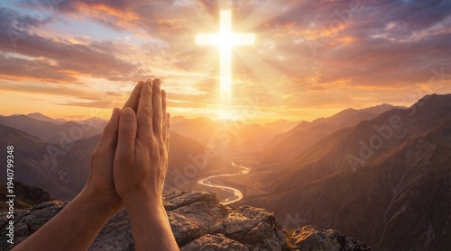 Praying hands with glowing cross in the sky over mountain landscape