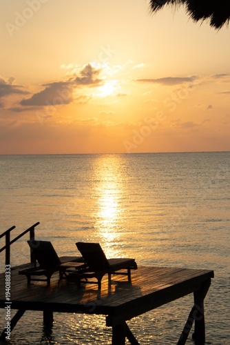 Luxury ocean sunset with lounge chairs on tropical beach deck