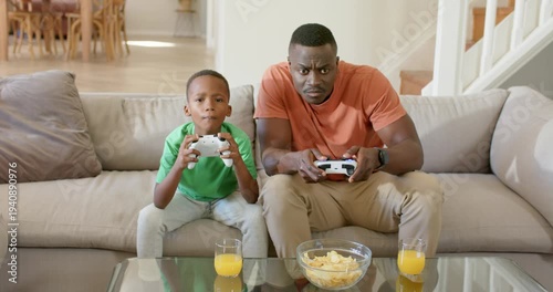 Game starting as African American father and son playing at home with white controllers competing