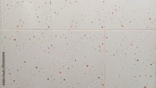Bild auf Leinwand Close up view of a white tiled wall composed of square ceramic tiles with visible grout lines and scattered gray, brown and orange speckles forming a terrazzo style surface pattern