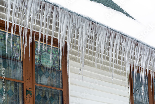 Snow-covered roof with long icicles hanging from a family house facade in winter, Boston, Massachusetts, USA
