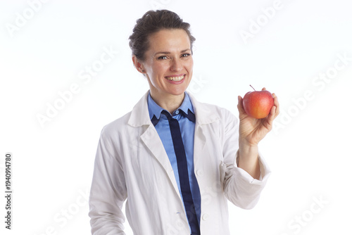 A professional female physician in a lab coat holds a red apple, representing healthy lifestyle choices, nutritional advice, and preventative medicine.