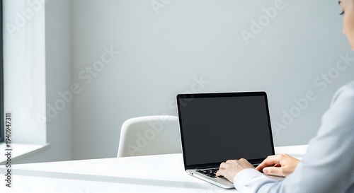 Focused professional working on a laptop computer at a bright, modern office desk