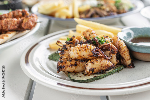 mediterranean style grilled squid with escabeche sauce and fries on white table at ibiza spain restaurant