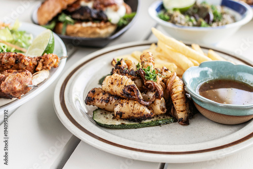 mediterranean style grilled squid with escabeche sauce and fries on white table at ibiza spain restaurant