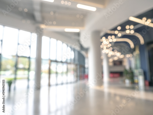 Blurred shopping mall entrance background with modern glass facade and bright interior lights. Abstract retail space, commercial building lobby and business environment backdrop with copy space.
